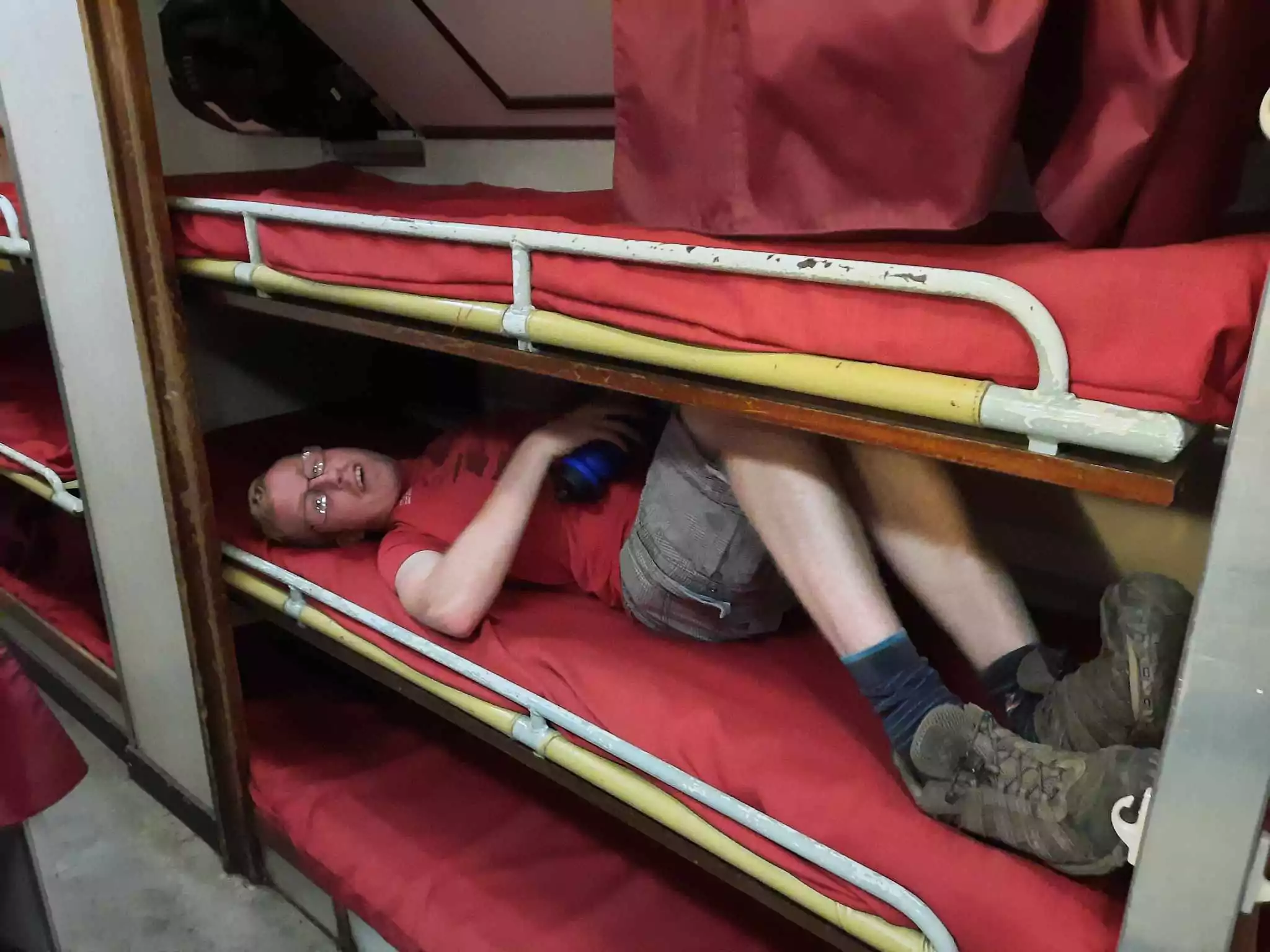 A man lying on a bunk bed on a Navy submarine